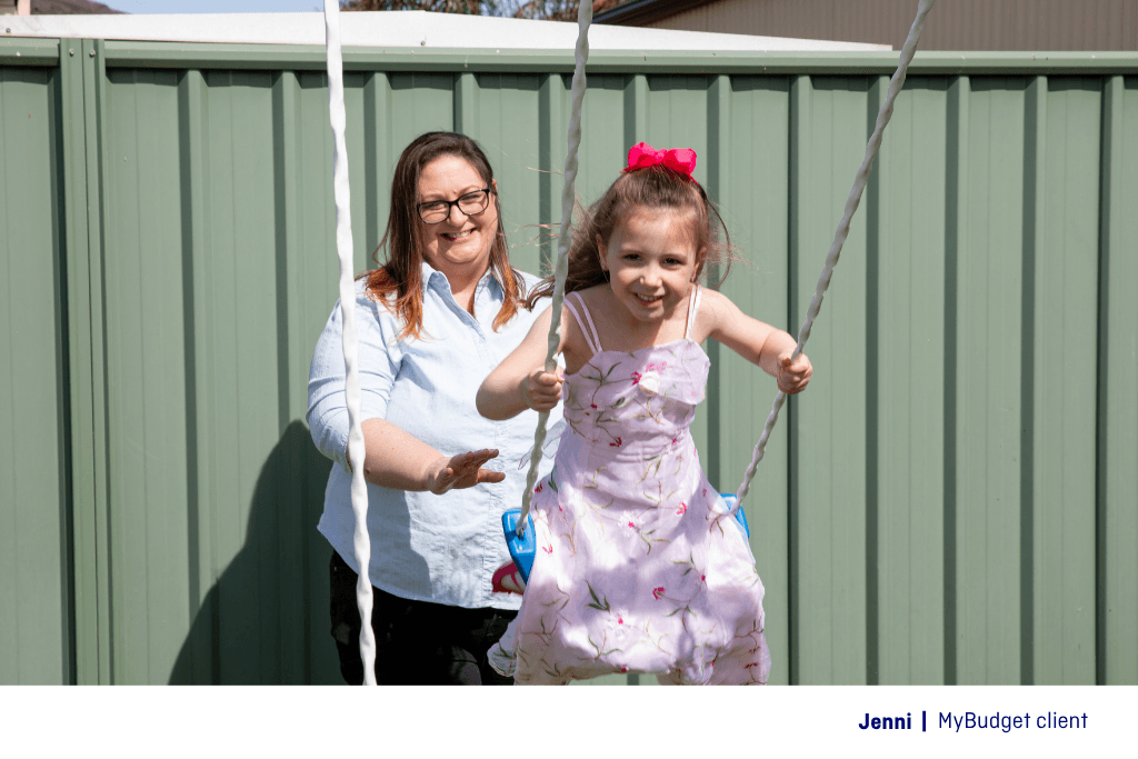 A single mother pushing her happy daughter on a swing